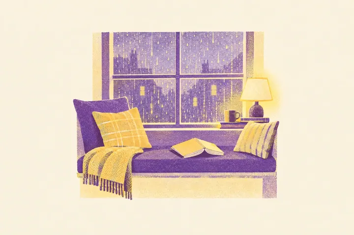 Illustration of a cosy window seat with cushions, a folded blanket and a paperback novel lying open face down, rain on the window and a lamp glowing
